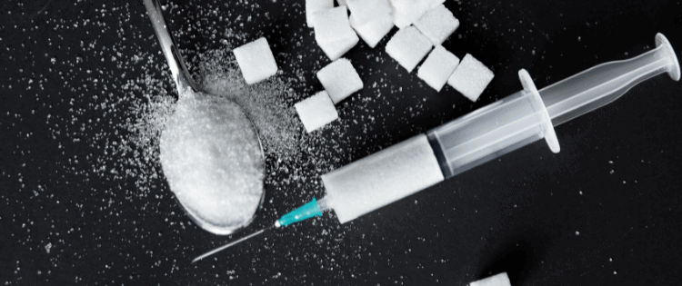 Diabetes illustrated with insulin shot, sugar cubes and spoon full of sugar